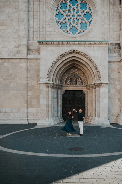 Budapest couple photoshoot: a turn beneath the church’s blue rose window The couple turning together in the circular paved area beneath Matthias Church’s blue rose window during a couple photoshoot in Budapest.
