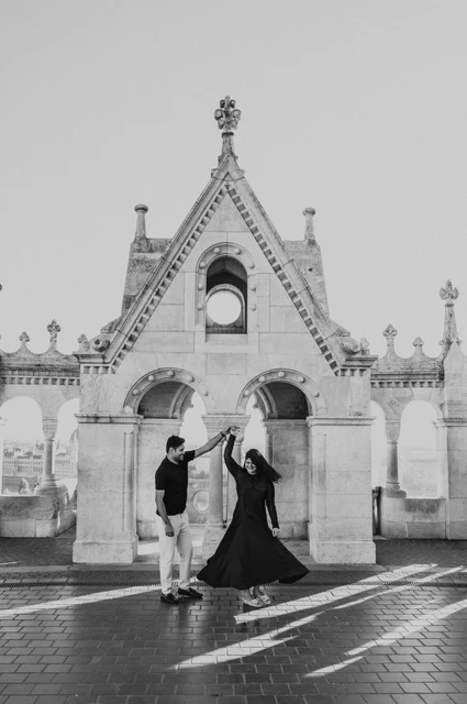 Budapest couple photoshoot: a turn in front of the Bastion’s gabled gateway in black and white Black-and-white photograph of the couple turning together in front of the ornate gabled gateway at Fisherman’s Bastion during a couple photoshoot in Budapest.