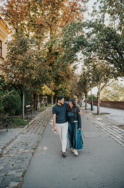 Budapest couple photoshoot: a walk together on Tóth Árpád promenade The couple walking hand in hand along Tóth Árpád promenade beneath the leafy trees during a couple photoshoot in Budapest.