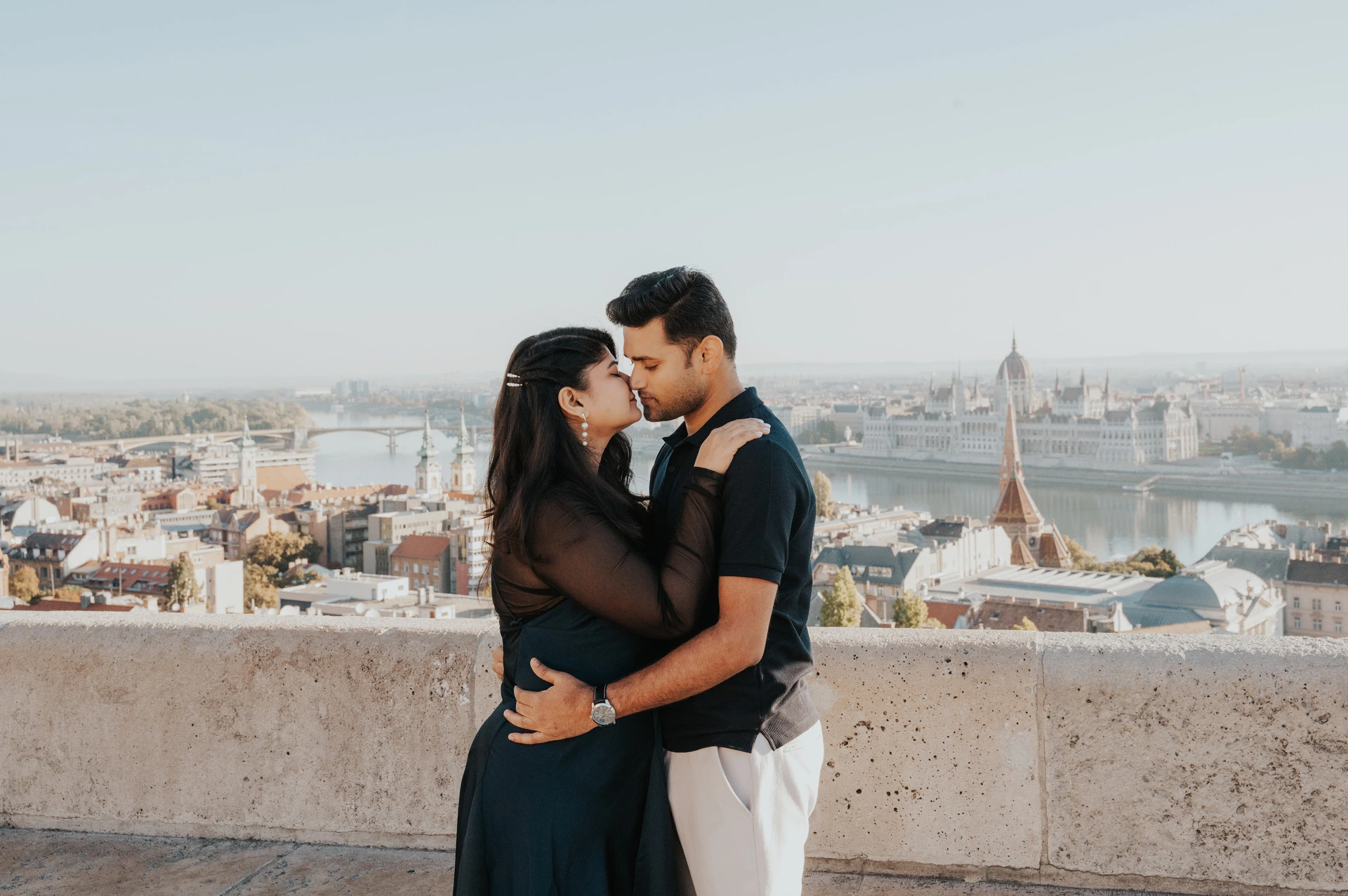 A landscape portrait of the couple embracing on a terrace at Fisherman’s Bastion during a couple photoshoot in Budapest.