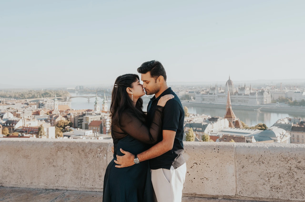 Budapest couple photoshoot: a terrace portrait with the city behind A landscape portrait of the couple embracing on a terrace at Fisherman’s Bastion during a couple photoshoot in Budapest.