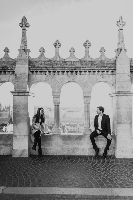 Black and white couple photoshoot in Budapest at Fisherman's Bastion Black and white portrait of a couple beside the arched windows at Fisherman's Bastion during their Budapest photoshoot