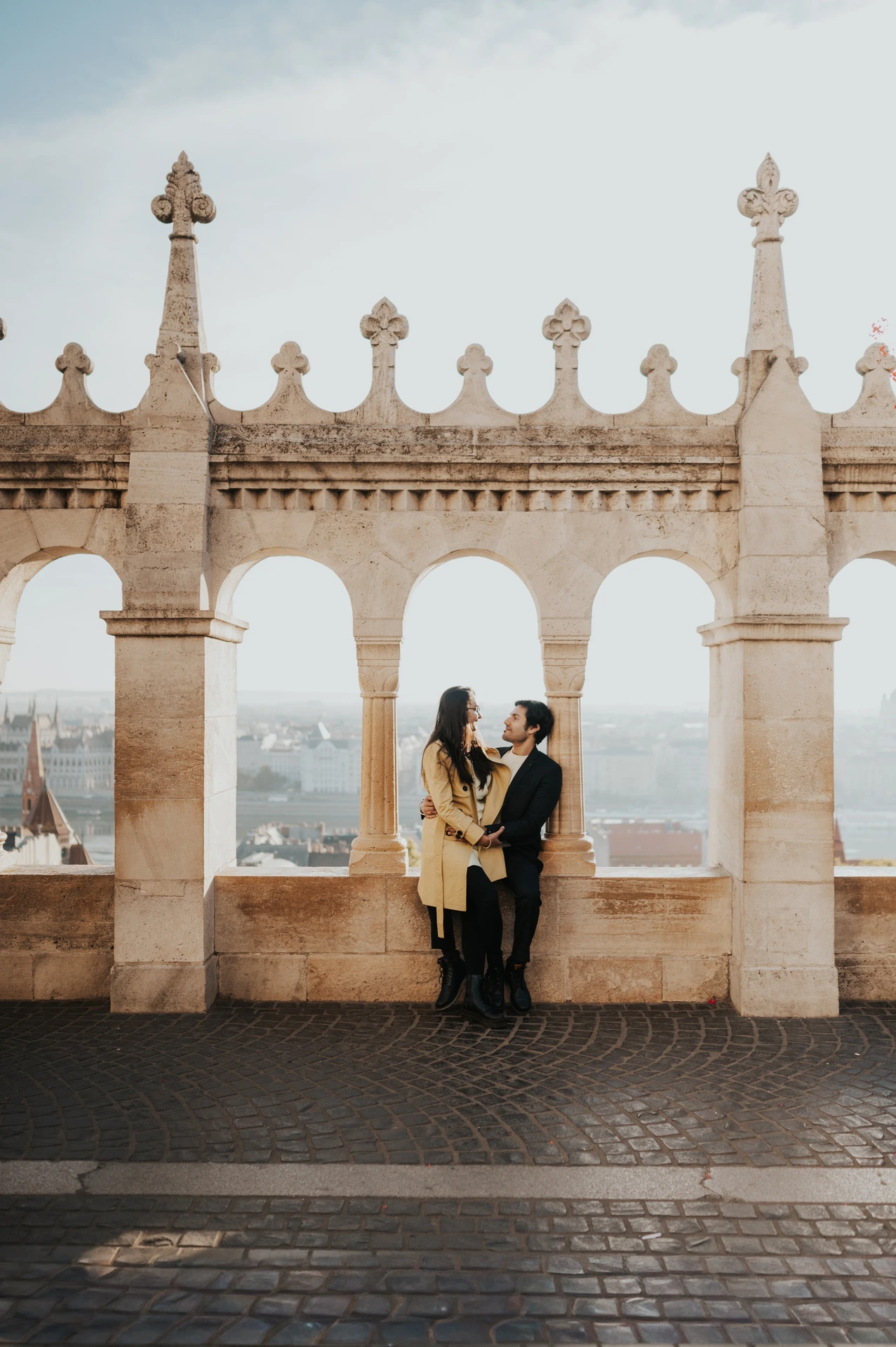 Couple embracing beneath the stone arches at Fisherman's Bastion during their couple photoshoot in Budapest