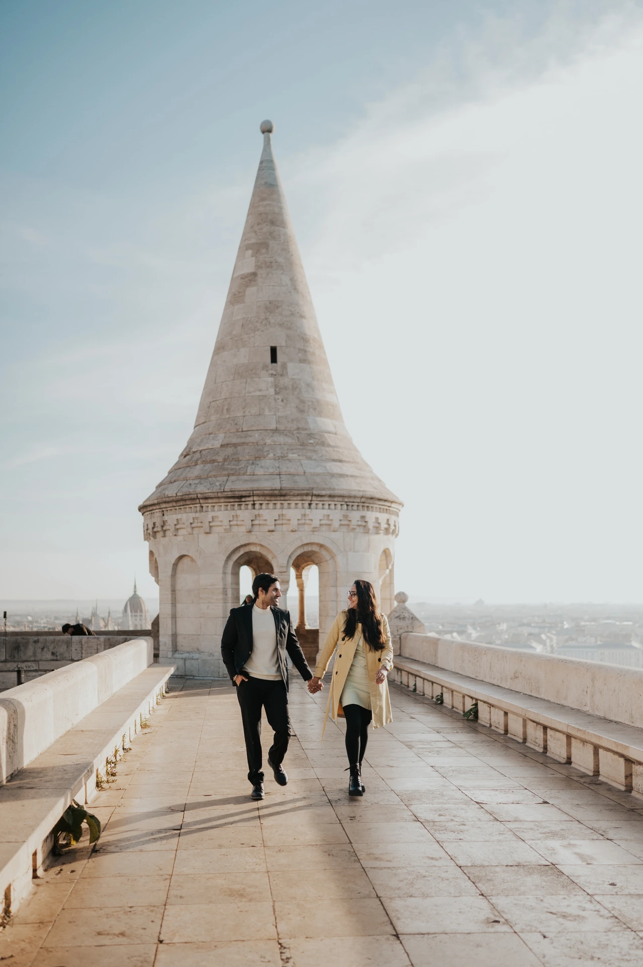 Couple looking at each other while walking along the Fisherman's Bastion terrace during their morning photoshoot in Budapest