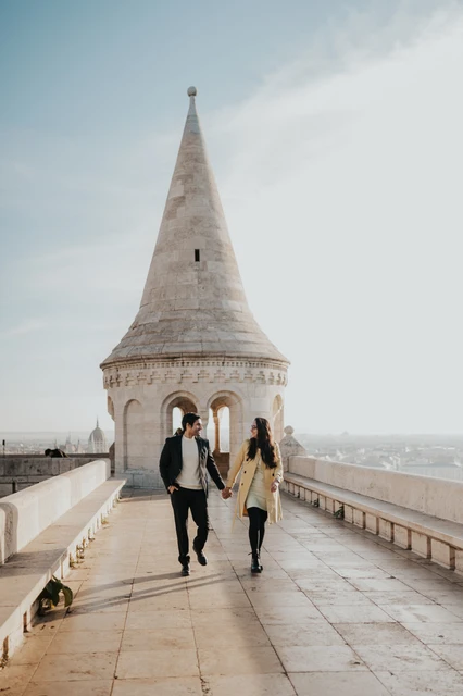 Morning photoshoot in Budapest on the Fisherman's Bastion terrace Couple looking at each other while walking along the Fisherman's Bastion terrace during their morning photoshoot in Budapest