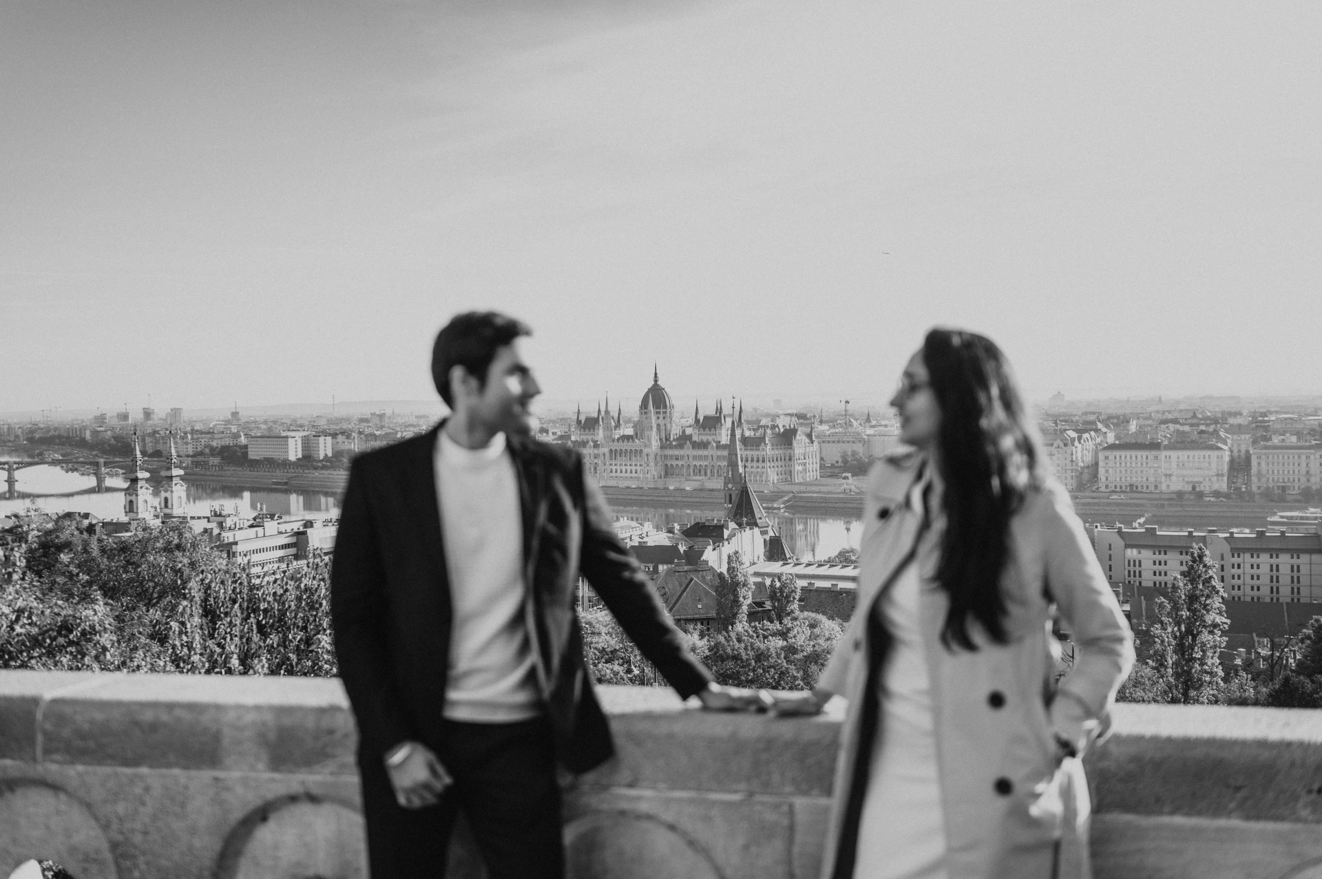Black and white landscape photograph of a couple holding hands at Fisherman's Bastion during their Budapest photoshoot