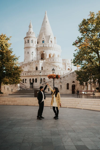 Budapest couple photoshoot with Fisherman's Bastion towers in the backdrop Couple facing each other and holding hands near the stone towers of Fisherman's Bastion during their Budapest photoshoot