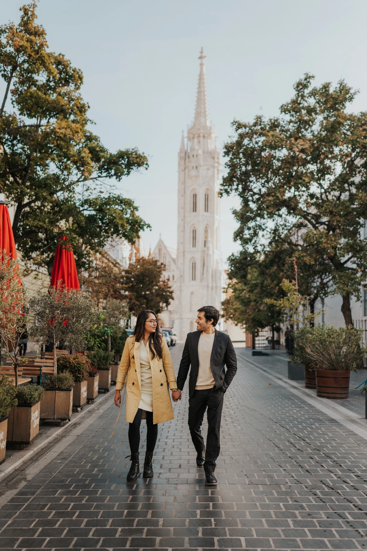 Couple walking towards the camera on a cobbled street near Fisherman's Bastion during their autumn photoshoot in Budapest