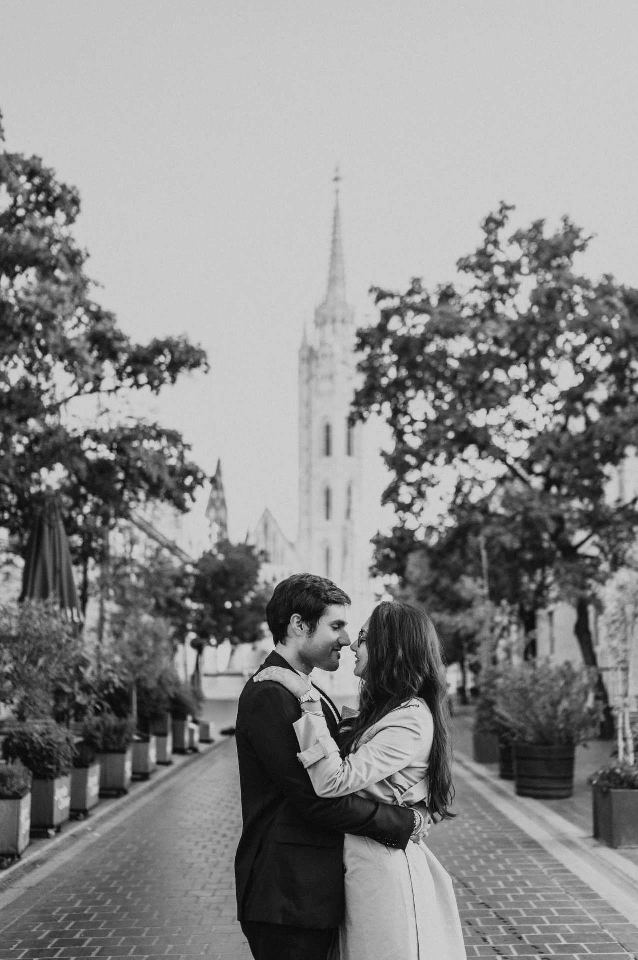 Black and white photograph of a couple embracing on a cobbled street near Fisherman's Bastion during their Budapest photoshoot