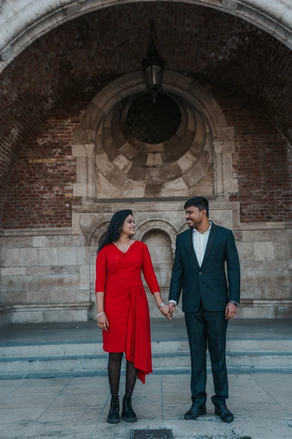 Smiles beneath the brick arch at a Budapest couple photoshoot The couple holding hands and smiling at one another in front of the brick arch and stone steps during their couple photoshoot in Budapest.