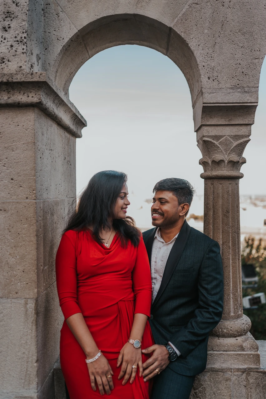 Budapest couple photoshoot beneath a small stone arch The couple smiling at one another beneath a small stone arch at Fisherman’s Bastion during their Budapest couple photoshoot.