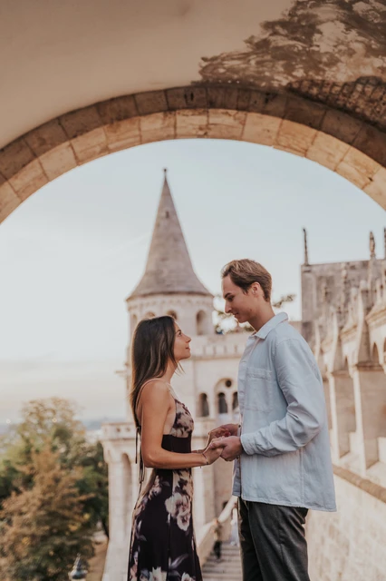 Budapest photoshoot with a stone turret behind the couple A closer view of the couple holding hands with a turret behind them during their Budapest photoshoot at Fisherman’s Bastion.