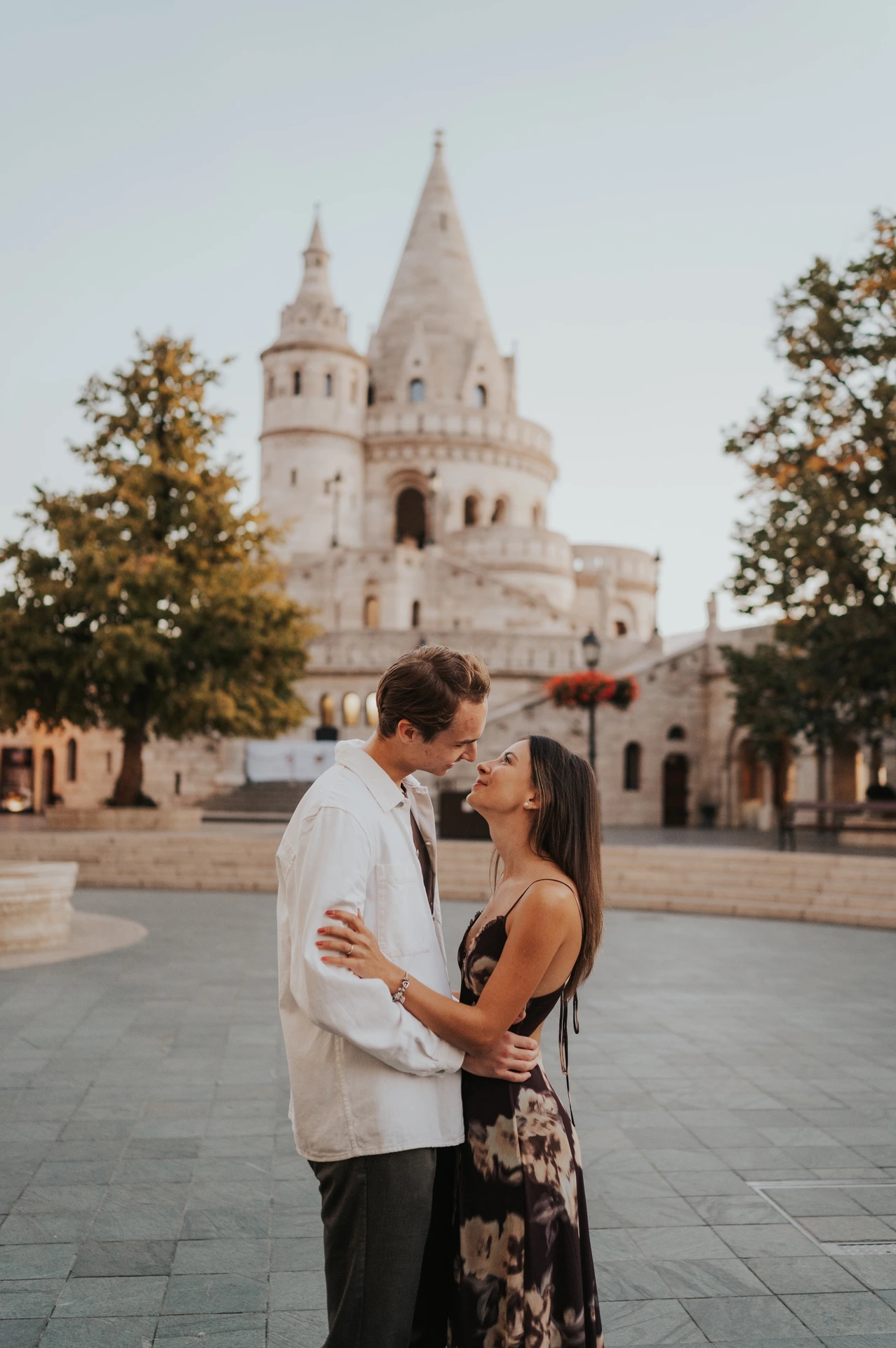 The couple kissing in the square with the towers of Fisherman’s Bastion in the background during their Budapest photoshoot.