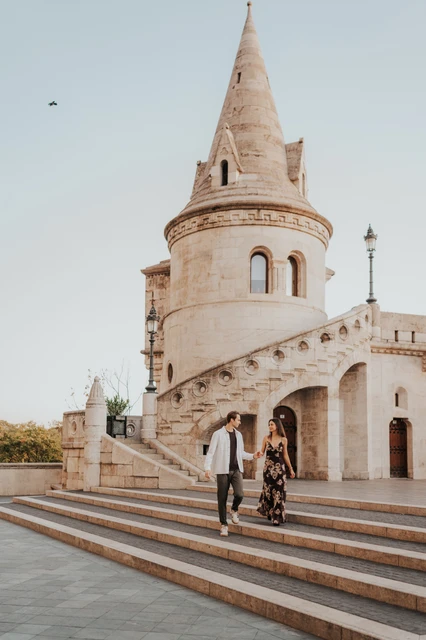 Budapest photoshoot walking down the steps beneath a turret The couple walking down the steps hand in hand during their Budapest photoshoot beneath the pointed turret of Fisherman’s Bastion.