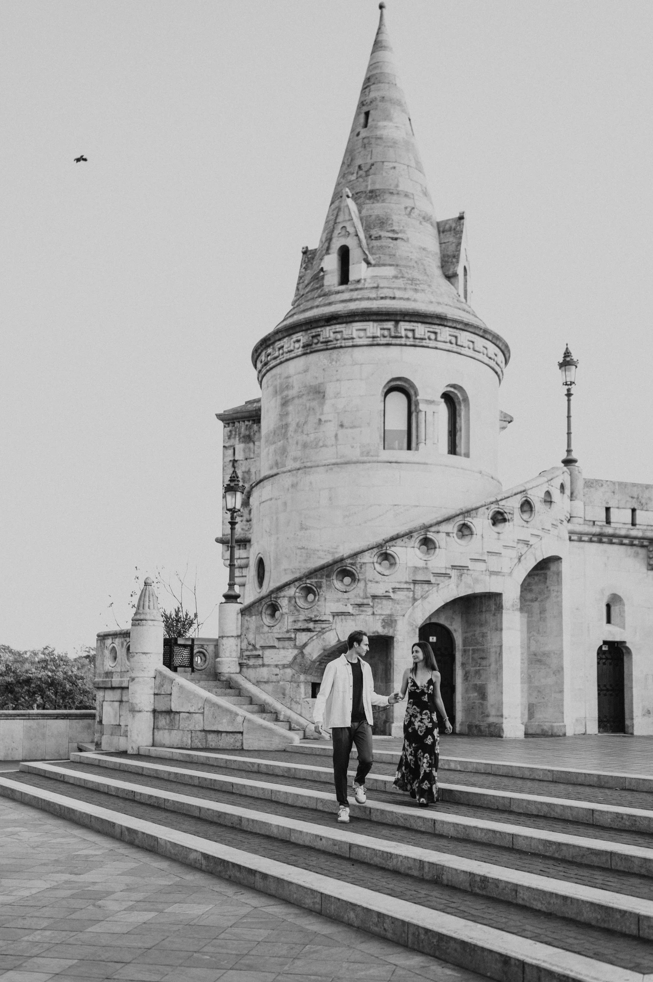 Black-and-white photograph of the couple walking down the stone steps during their Budapest photoshoot at Fisherman’s Bastion.