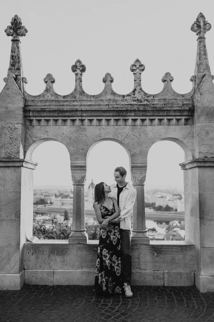 Budapest photoshoot at the terrace arches in black and white Black-and-white portrait of the couple embracing beside the open terrace arches during their Budapest photoshoot at Fisherman’s Bastion.