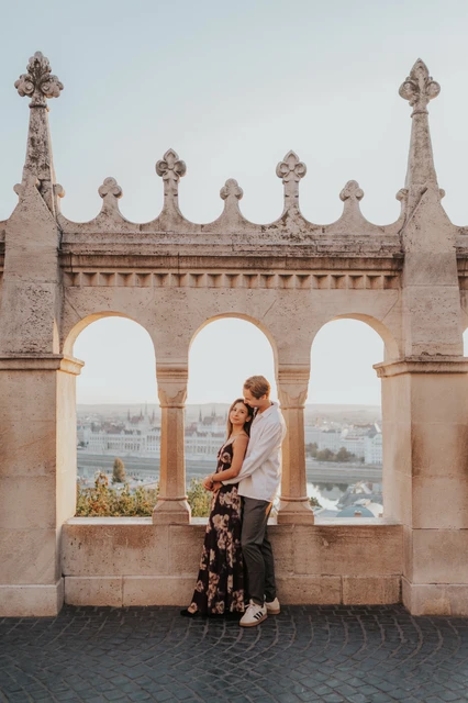 Budapest photoshoot embracing on the Fisherman’s Bastion terrace The couple leaning close together on the terrace during their Budapest photoshoot, framed by the decorative arches of Fisherman’s Bastion.