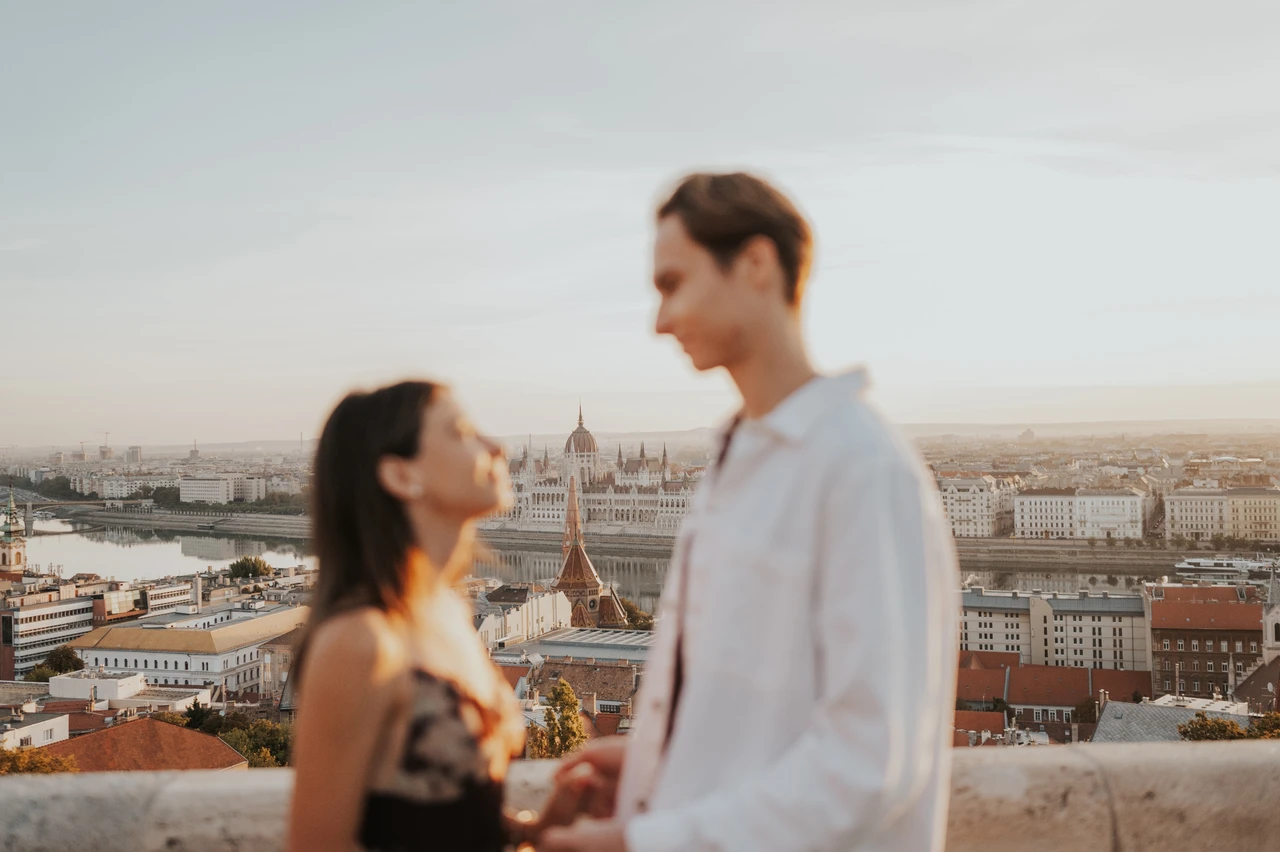 Budapest photoshoot with Parliament behind the softly focused couple Soft-focus portrait of the couple facing each other during their Budapest photoshoot, with Parliament sharply visible in the backdrop.