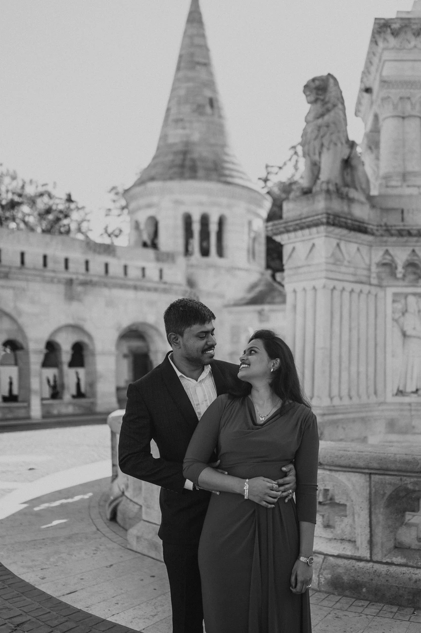 Budapest photoshoot beside the turret in black and white Black-and-white portrait of the couple smiling at one another beside the carved stone monument and a Fisherman’s Bastion turret during their Budapest photoshoot.