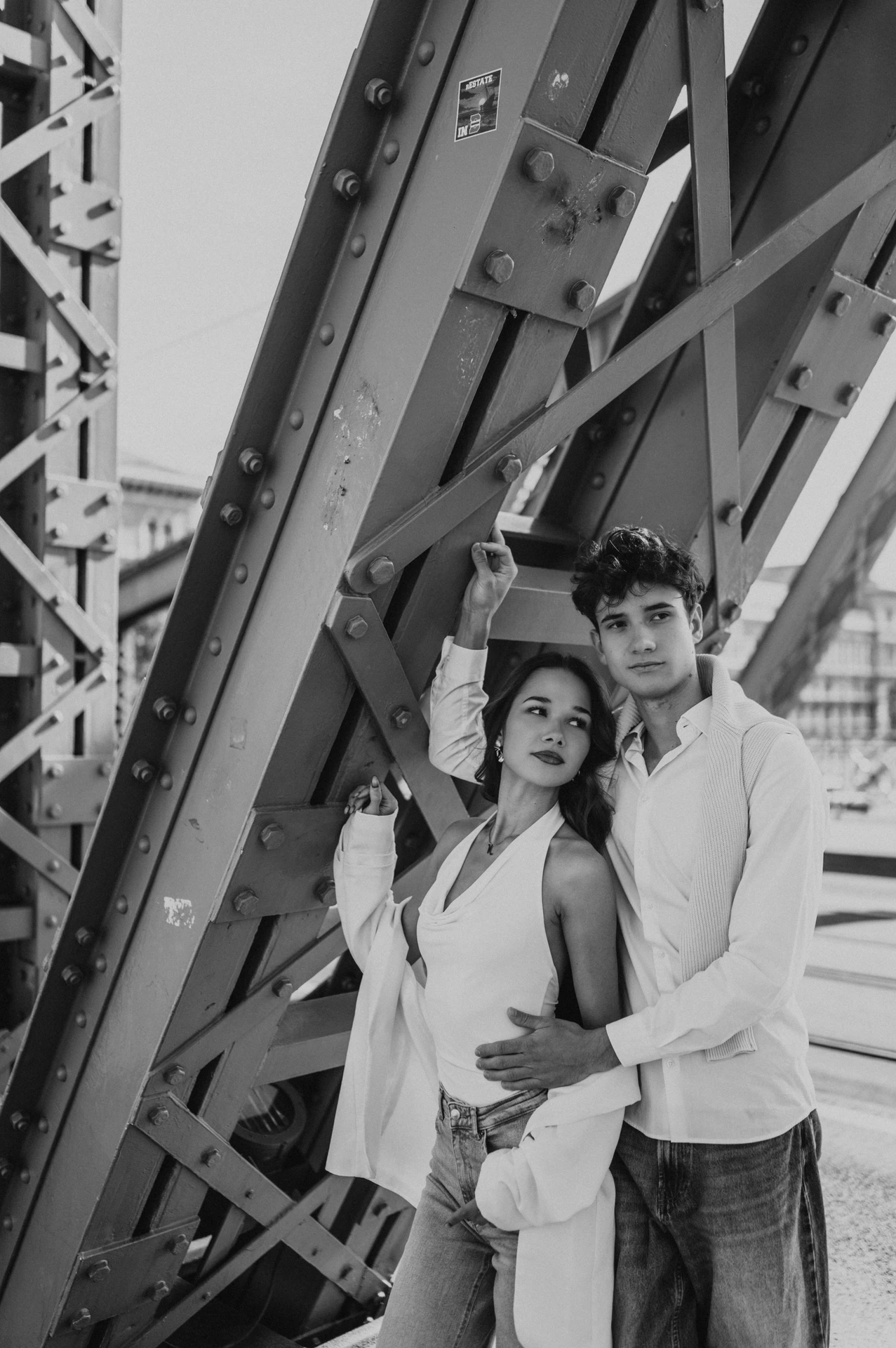 Black-and-white portrait of the couple together beneath the steel beams during their Budapest photoshoot on Liberty Bridge.