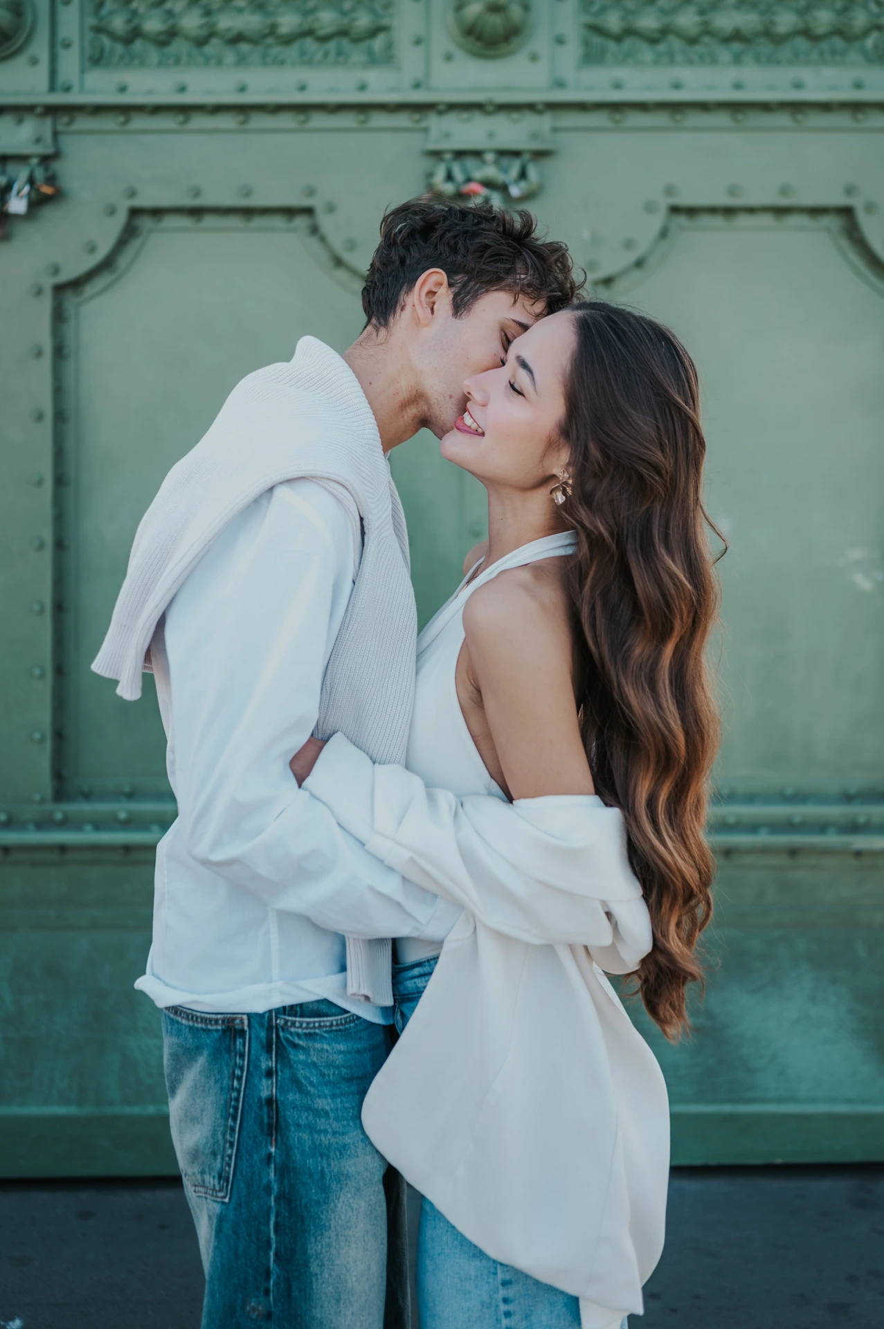 A close portrait of the couple embracing and kissing against the green bridge structure during their Budapest photoshoot on Liberty Bridge.