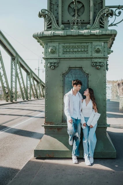 Budapest photoshoot beside a decorative Liberty Bridge pillar The couple standing together against an ornate green bridge pillar during their Budapest photoshoot on Liberty Bridge.