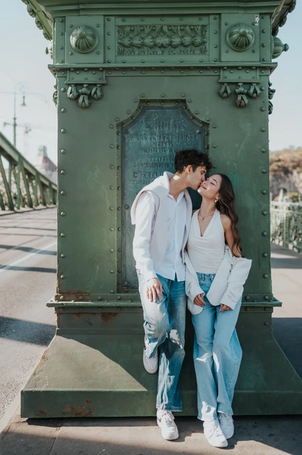 Close couple photoshoot in Budapest beside the Liberty Bridge pillar The couple leaning close together beside the decorative green pillar during their Budapest photoshoot on Liberty Bridge.