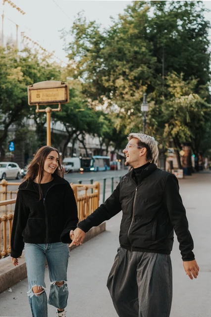 Budapest photoshoot holding hands near the metro entrance The couple smiling towards each other and holding hands beside the metro entrance during their Budapest photoshoot.