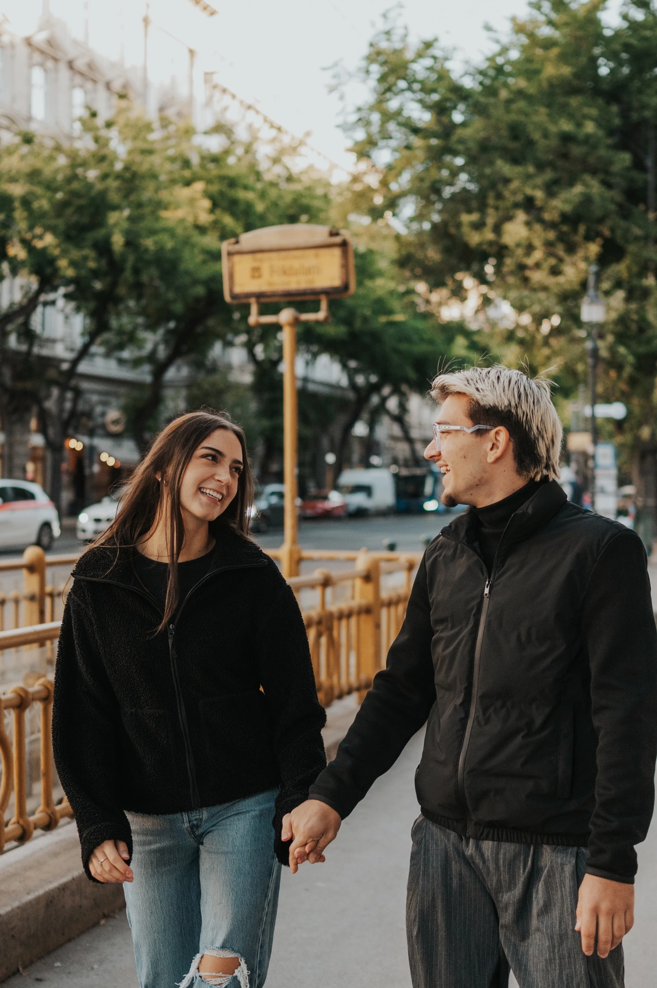 A closer portrait of the couple looking towards each other beside the yellow metro railings during their Budapest photoshoot.