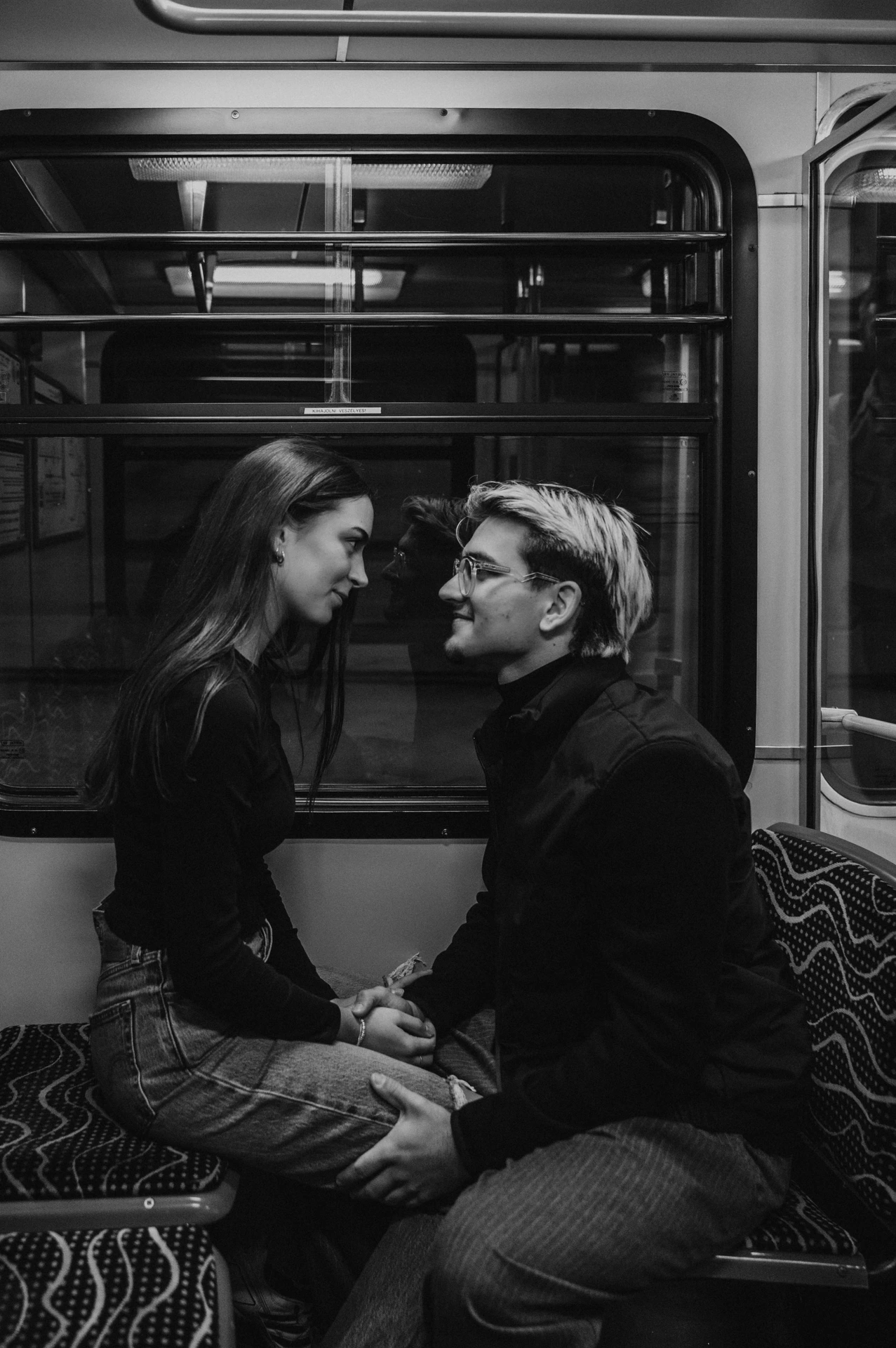 Black-and-white portrait of the couple seated together and holding hands during their Budapest photoshoot inside the metro.
