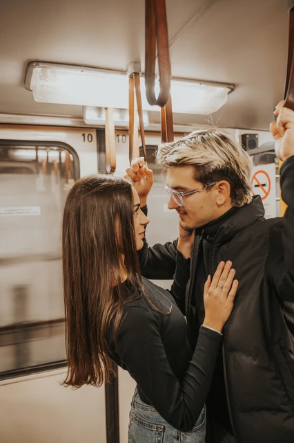 Budapest photoshoot together beneath the metro handrail The couple facing each other beside the metro window during their Budapest photoshoot, with him holding an overhead rail.