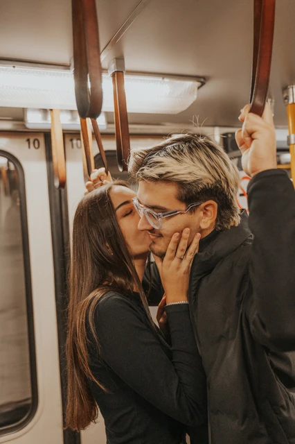 Budapest couple photoshoot sharing a kiss beside the carriage window A close portrait of the couple kissing beside a metro window during their Budapest photoshoot, with her hand resting against his cheek.