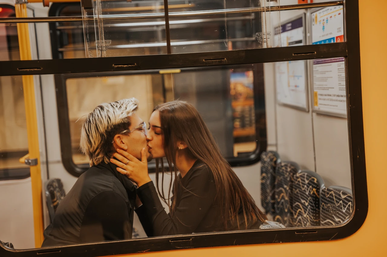 Photoshoot in Budapest framed by a yellow metro carriage window The couple kissing on the patterned seats during their Budapest photoshoot, framed by the window of the yellow metro carriage.