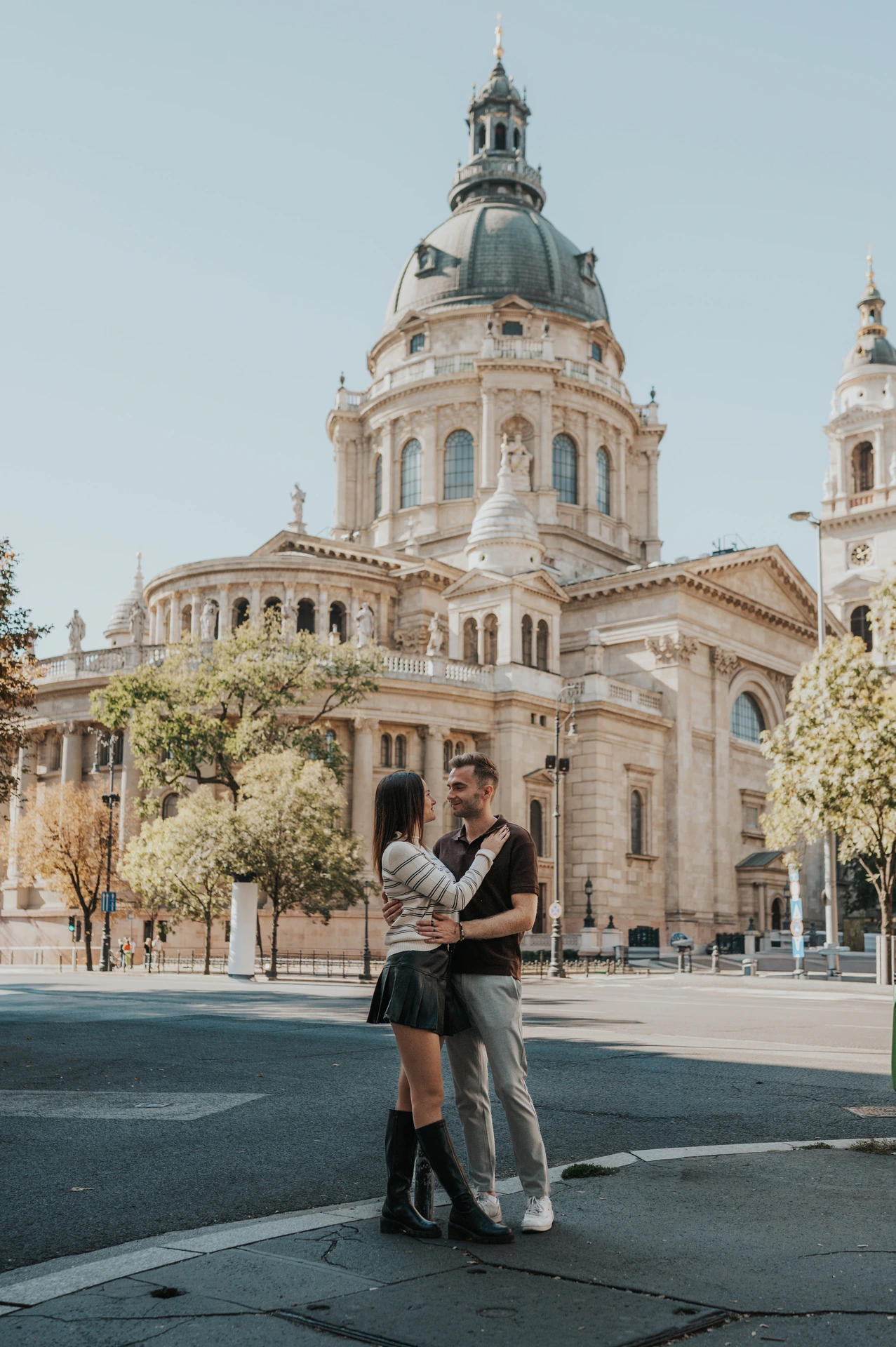 The couple embracing in the square with St Stephen’s Basilica and its dome behind them during a couple photoshoot in Budapest.