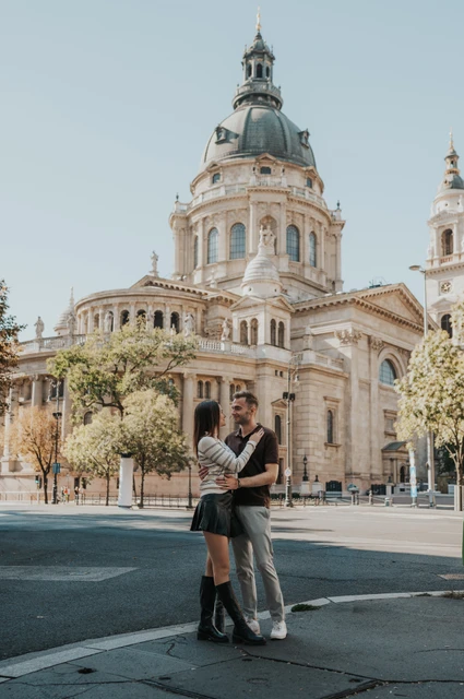 The couple embracing in the square with St Stephen’s Basilica and its dome behind them during a couple photoshoot in Budapest.