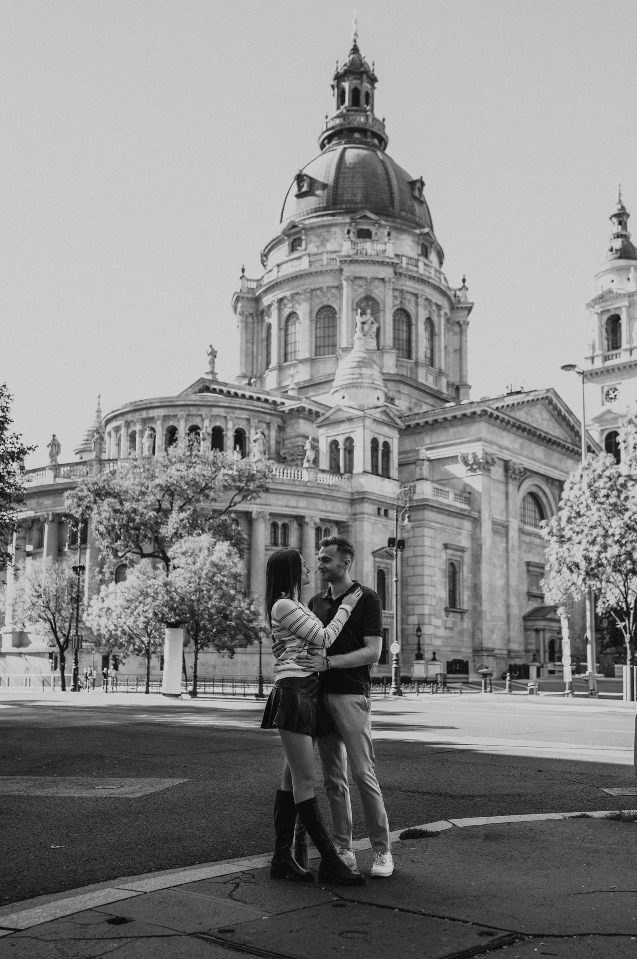 Black-and-white photograph of the couple standing close in the square in front of St Stephen’s Basilica during a couple photoshoot in Budapest.