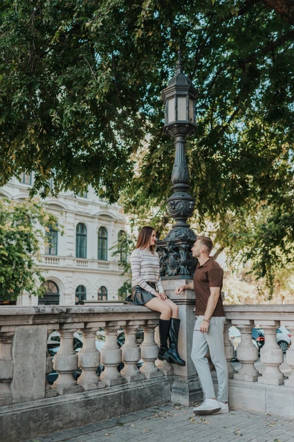 Budapest couple photoshoot: a shaded portrait near the Basilica The couple standing close by a stone balustrade under trees near St Stephen’s Basilica during a couple photoshoot in Budapest.