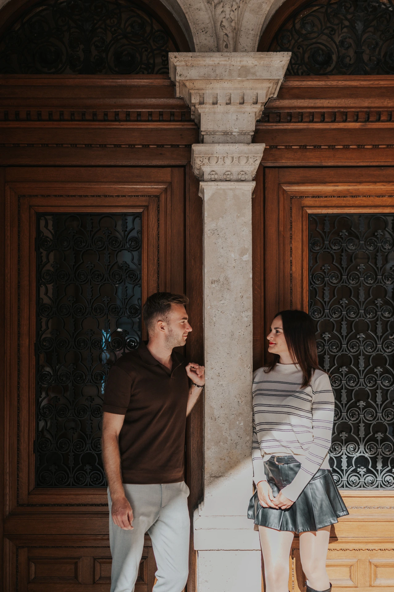The couple standing on either side of a stone column outside the Opera during a couple photoshoot in Budapest.