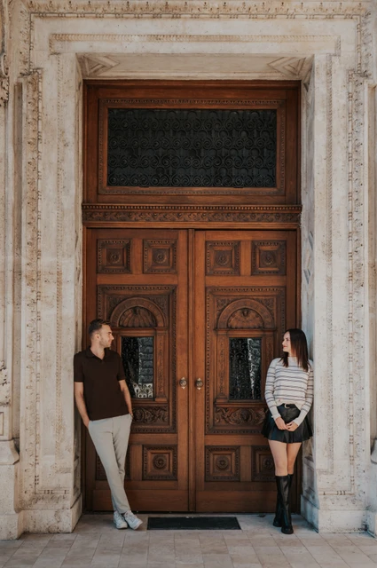 Budapest couple photoshoot: by the Opera’s carved wooden doors The couple standing apart in front of the Opera’s large carved wooden doors during a couple photoshoot in Budapest.