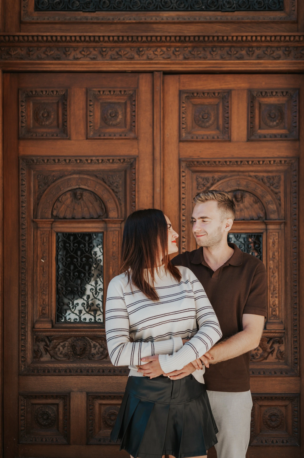 A close portrait of the couple in front of the Opera’s ornate wooden doors during a couple photoshoot in Budapest.