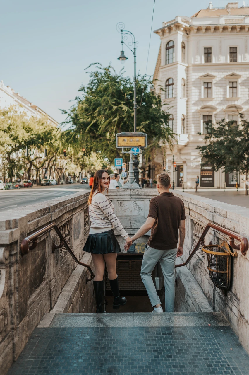 Budapest couple photoshoot: walking down the Opera metro steps The couple holding hands as they step down into the Opera metro entrance during a couple photoshoot in Budapest.