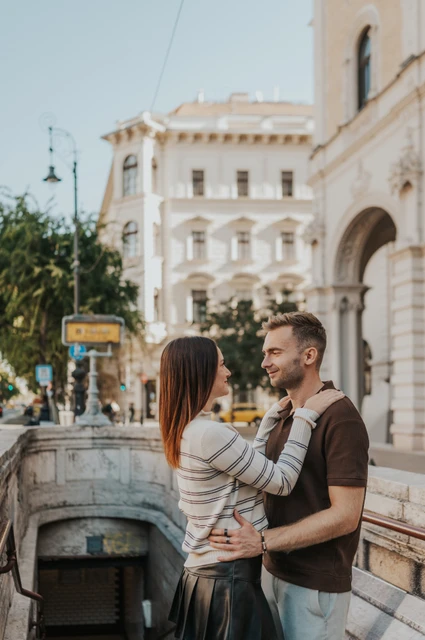 Budapest couple photoshoot: an embrace beside the Opera metro steps The couple embracing at the top of the stone steps to Opera metro station during a couple photoshoot in Budapest.