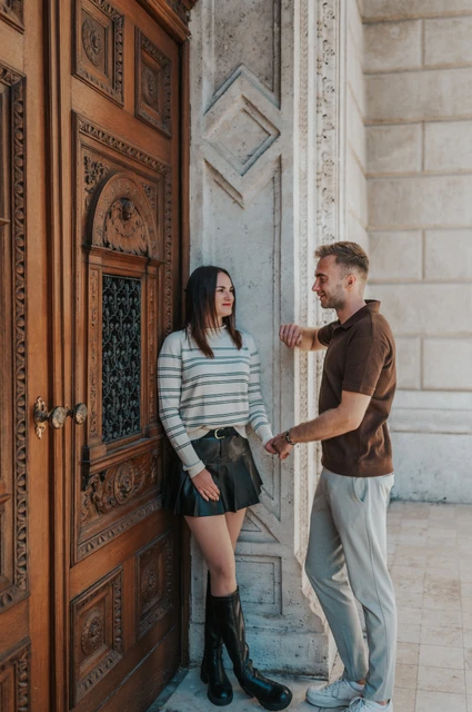 Budapest couple photoshoot: a moment by the Opera doorway The couple looking towards each other beside the Opera’s carved wooden doorway during a couple photoshoot in Budapest.