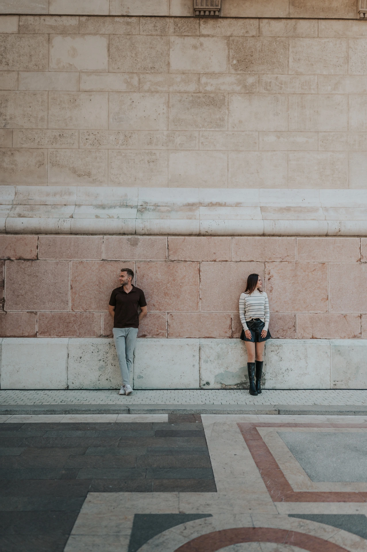 The couple standing apart against St Stephen’s Basilica’s tall pale stone wall during a couple photoshoot in Budapest.