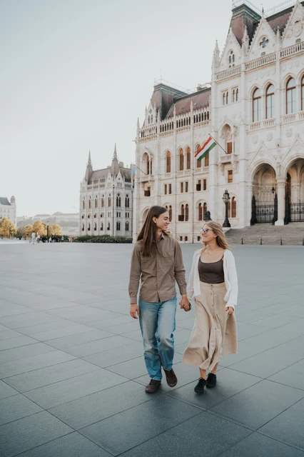 Budapest photoshoot holding hands outside Parliament The couple smiling towards each other as they walk across the square during their Budapest photoshoot outside Parliament.