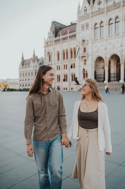 Budapest photoshoot with Parliament’s arches in the backdrop The couple holding hands and looking towards each other during their Budapest photoshoot, with Parliament’s arches behind them.