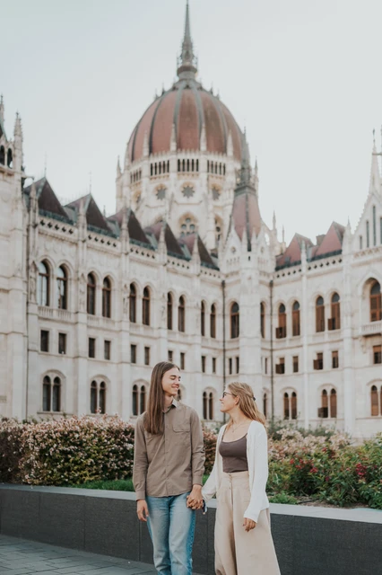 Budapest photoshoot sharing a look in front of Parliament’s dome The couple looking towards each other beside the garden during their Budapest photoshoot, with the Hungarian Parliament filling the background.