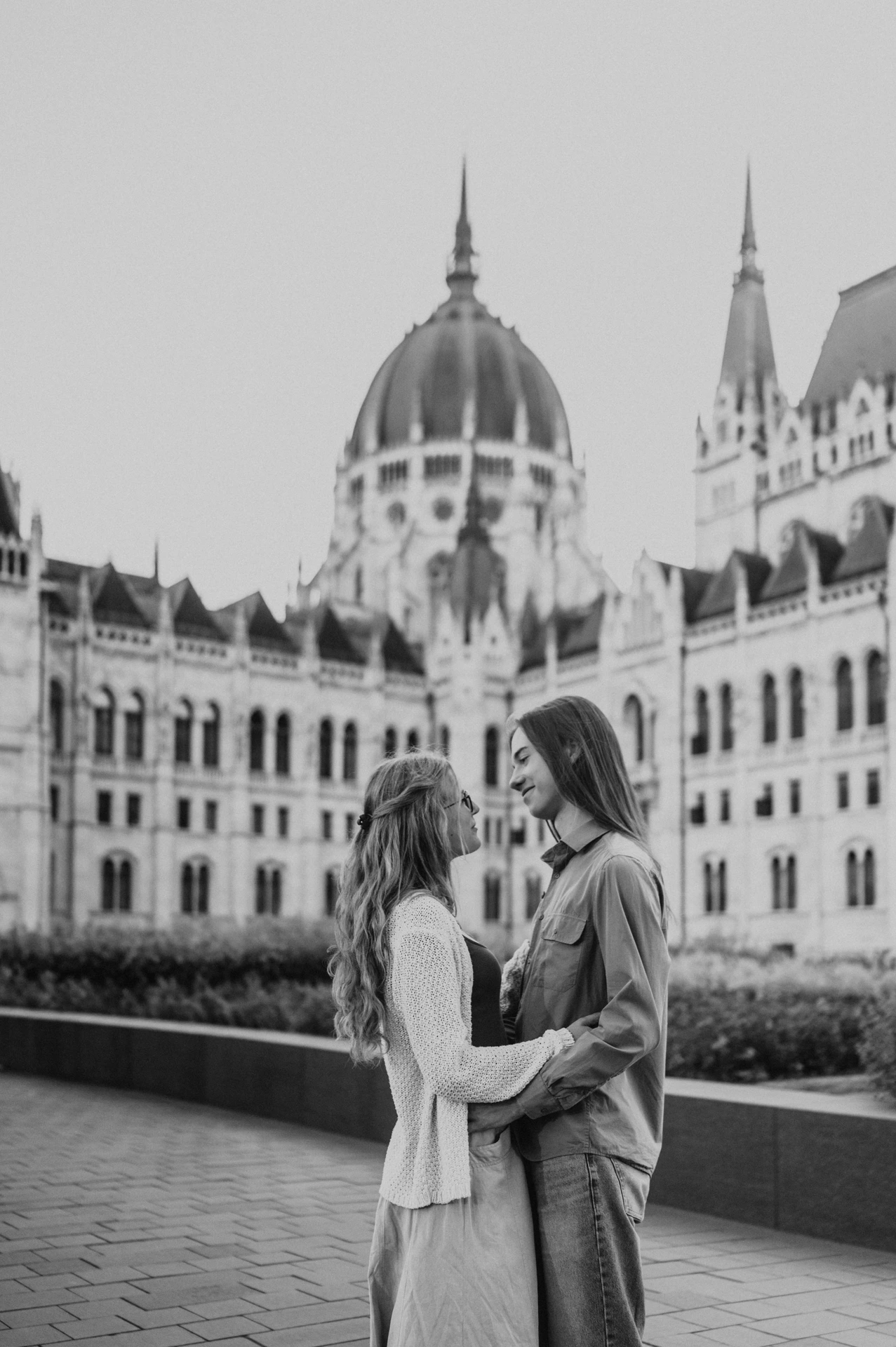 Black-and-white portrait of the couple embracing during their Budapest photoshoot, framed by the Hungarian Parliament’s dome.