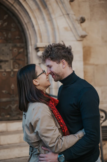 Budapest couple photoshoot: a close portrait beside the wooden door A close portrait of the couple smiling towards each other beside Matthias Church’s carved wooden door during a couple photoshoot in Budapest.