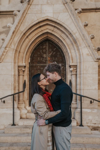 Budapest couple photoshoot: an embrace outside Matthias Church The couple embracing and leaning close outside the pointed wooden doorway at Matthias Church during a couple photoshoot in Budapest.
